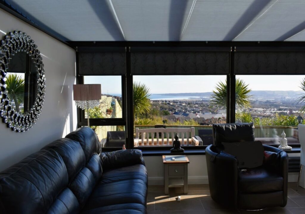 A large black lean to conservatory with a privacy wall and symmetrical windows