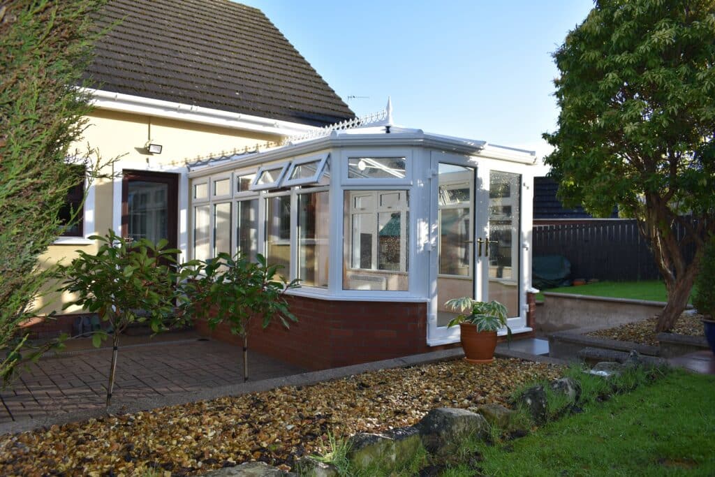 Large white conservatory with top opening windows and matching french doors