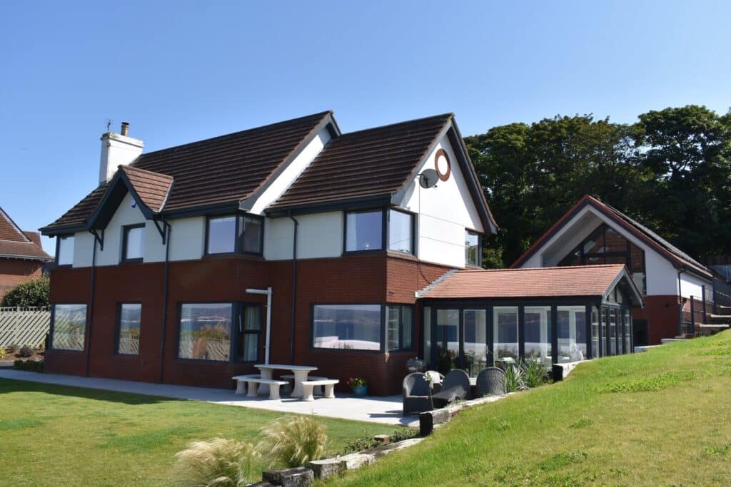 Anthracite grey aluminium roofline with matching bargeboards, downspouts and fascia on a home and sunroom in Northern Ireland