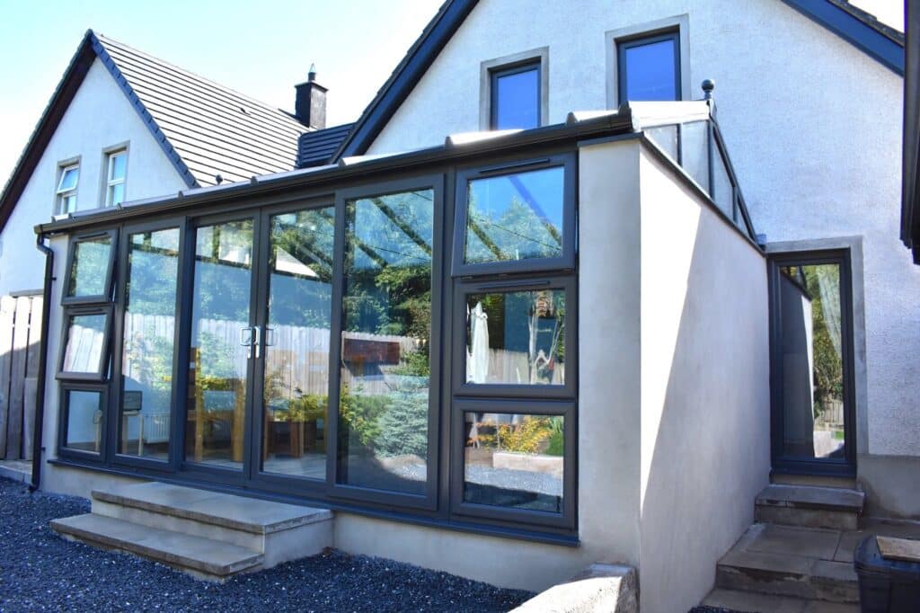 Large double hipped conservatory with privacy walls and sliding patio doors