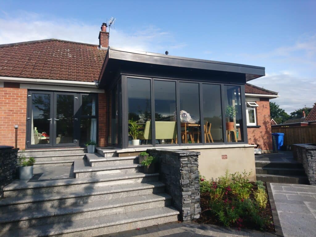 Elegant pod sunroom featuring corner glazing and raised patio area by Budget Designer HomeWorks in Northern Ireland
