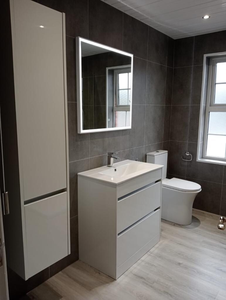 Modern bathroom with backlit mirror and bathroom wall panels by Budget Designer HomeWorks